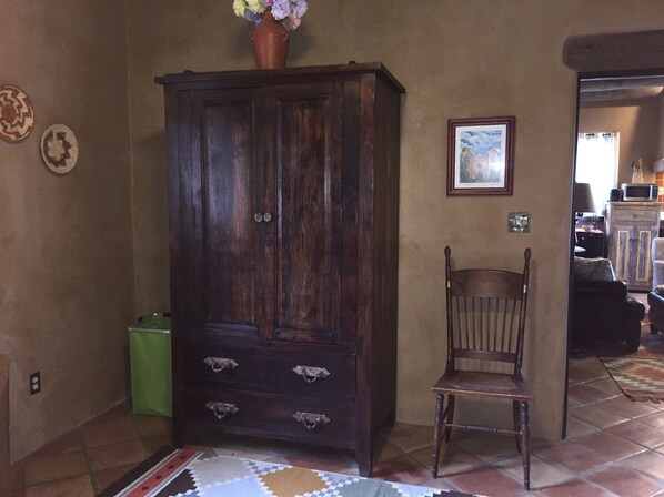 A room with a large wooden cabinet, a chair, and a patterned rug.