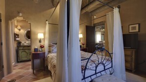 A bedroom with a four-poster bed, a nightstand, a dresser, and a mirror. - Authentic Santa Fe Casita with Views on the Edge of Town (Santa Fe)