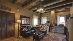 A cozy living room with a fireplace, a dining area, and a kitchen with modern appliances. - Authentic Santa Fe Casita with Views on the Edge of Town (Santa Fe)