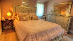 A bedroom with a large bed, a bedside table with a lamp, a dresser, and a mirror. -  Modern country cottage that is dog friendly with a fenced-in yard.  (Columbia)