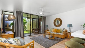 Ein modernes Wohnzimmer mit einer Couch, Sesseln, einem Esstisch und einem Deckenventilator.