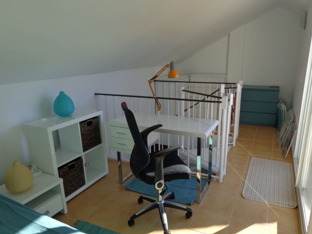 A room with a desk, chair, shelves, and a crib.