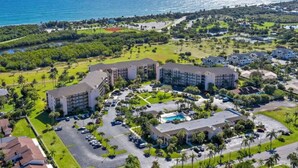 An aerial view of a resort with multiple buildings, a parking lot, and a pool area.
