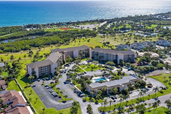 Eine Luftaufnahme eines Resorts mit mehreren Gebäuden, einem Parkplatz und einem Poolbereich.