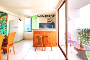 A kitchen with a wooden bar stool set, a refrigerator, and a microwave. - Ocean View 2BR Condo, One Block from the Beach in the Hotel Zone  (Puerto Vallarta)