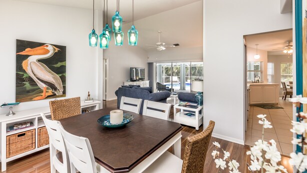 A spacious living area with a dining table, sofas, and a large painting of a pelican. - Tropical Perfection!  3 BR/2 BA & HEATED POOL! Close to beaches, WiFi (Sebastian)