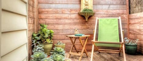 A wooden deck with potted succulents, a small table with a green cloth, and a wooden easel with a green cloth.