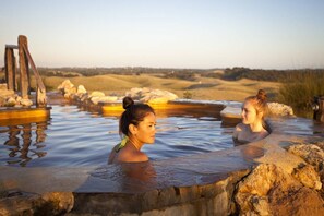 A hot spring area with natural rock formations and a wooden structure.