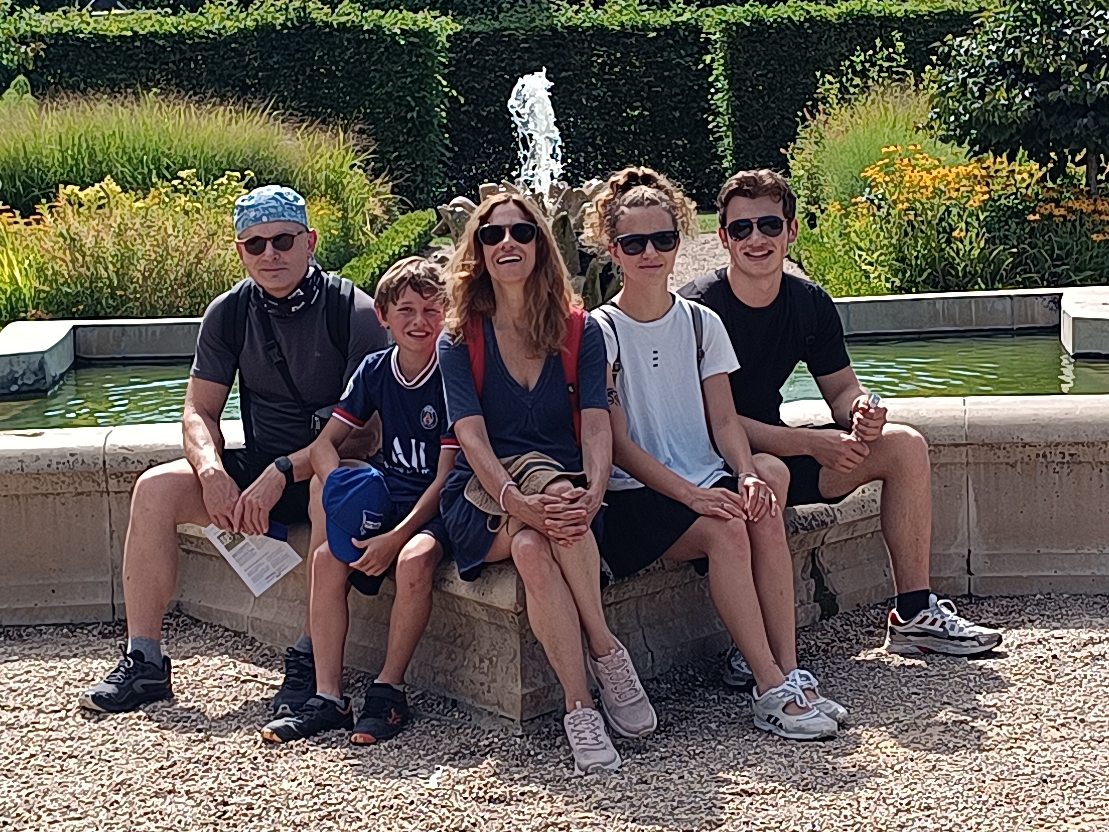 A group of people sitting on a stone bench near a water feature.