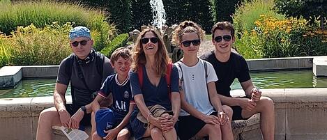 A group of people sitting on a stone bench near a water feature.