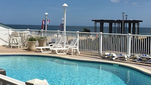 A pool area with lounge chairs and a view of the ocean. - Virginia Beach Oceanfront Studio, Lawn, Boardwalk, Pool, Beach (Virginia Beach)