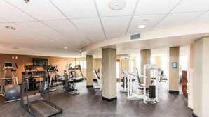 Un gimnasio con cintas de correr, elípticas y equipo de pesas.