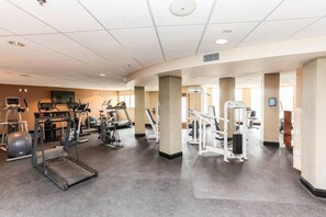 Une salle de sport équipée de tapis de course, de vélos elliptiques et d'appareils de musculation.