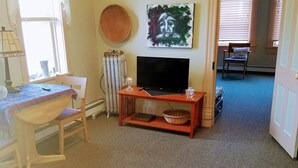 A living room with a sofa, a table with a lamp, a TV on a stand, and a painting on the wall. - Fully equipped apartment for short term vacation rentals! (Calumet)