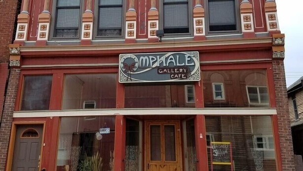 A two-story building with a sign reading "J.W. Isakson 1894" at the top. The ground floor has a sign for "MPHALE Gallery Cafe." - Fully equipped apartment for short term vacation rentals! (Calumet)