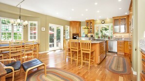 A spacious kitchen with wooden cabinets, a dining area with chairs, and a large window providing natural light.