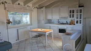 A kitchen with white cabinets, a wooden table, and a window with a view of greenery. - Appartment with unique view on the Garda Lake (Desenzano del Garda)
