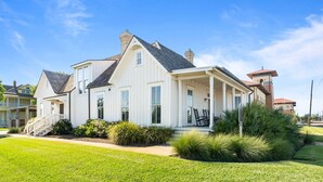 Une maison à deux étages avec un porche, une cheminée et une pelouse bien entretenue.