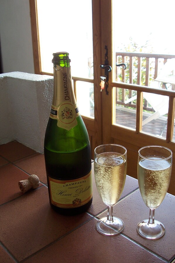 A bottle of champagne and two glasses on a tiled surface near a window. - Beautiful cottage in Most Beautiful Village (Belvès)