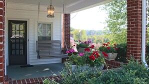 A covered porch with a bench, hanging lantern, and potted plants.