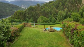 Un paisaje exuberante y verde con una piscina, rodeado de un bosque denso y montañas al fondo.