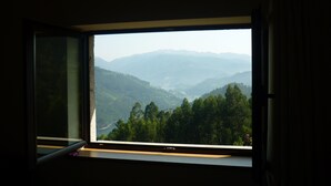 Una ventana con vistas a un valle y montañas.