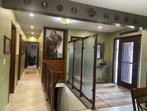 A hallway with a staircase, a bull painting, and a door with a mirror and a sign. - Renovated Home on Acre. Sunset Cliff Experience. Pets. Two Full Bathrooms. (Rapid City)