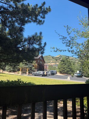 A view of a building with a parking lot and vehicles, surrounded by trees and hills.