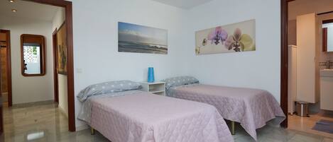 A bedroom with two beds, a nightstand, and a painting of flowers.