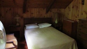 A wooden cabin room with a bed, a chair, a nightstand, and a lamp. - Spectacular Location  Reasonably Priced (Belgrade)