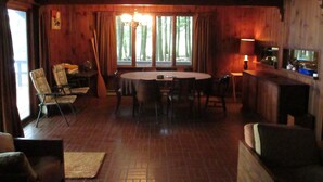 A wooden interior with a round dining table surrounded by chairs, a fireplace, and a window with curtains. - Spectacular Location  Reasonably Priced (Belgrade)