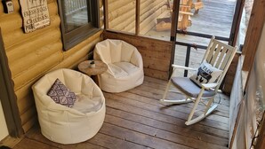 A wooden deck with two bean bags and a rocking chair.