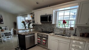 A modern kitchen with white cabinets, a stainless steel sink, and a built-in microwave. - Fantastic Lakefront Home With Private Yard and Pool (Fort Lauderdale)