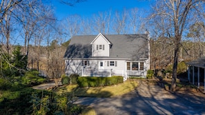 A two-story house with a front porch, a garage, and a driveway leading to the house.