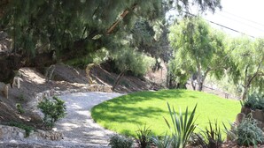 A landscaped garden with a gravel path, green grass, and various plants. - Malibu Getaway-Relaxation Destination-Ocean view-Beaches, Hiking, Shops, Dining (Malibu)