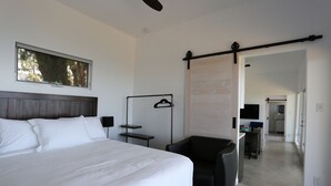A modern hotel room with a large bed, a desk, a chair, a coat rack, and a view of the hallway. - Malibu Getaway-Relaxation Destination-Ocean view-Beaches, Hiking, Shops, Dining (Malibu)