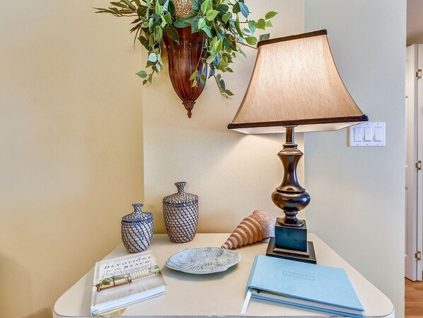 A table with a lamp, a book, a vase, and a shell.