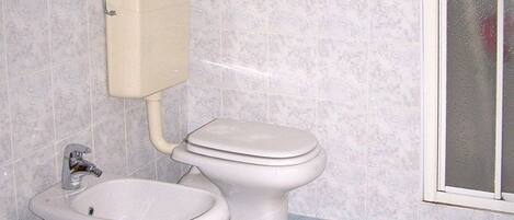 A bathroom with a toilet, bidet, and sink.