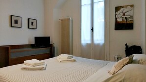 Une chambre d’hôtel avec un lit, un bureau, un radiateur et une fenêtre avec des rideaux.