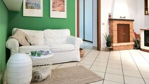 Un salon avec un canapé blanc, un mur d’accent vert et une cheminée.