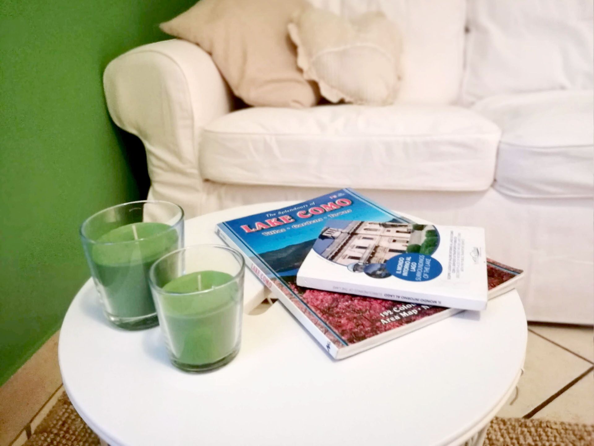 Een witte tafel met een boek getiteld 'Lake Como' en twee glazen groene vloeistof.