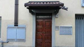 Un bâtiment doté d’une double porte en bois, d’un petit auvent et d’une enseigne portant le numéro « 27 » au-dessus de la porte.
