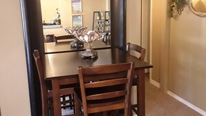 A dining area with a dark wooden table and matching chairs, a decorative metal centerpiece, and a view into the adjacent kitchen area. - Cozy guest apartment conveniently located to all Woodland Park attractions (Woodland Park)