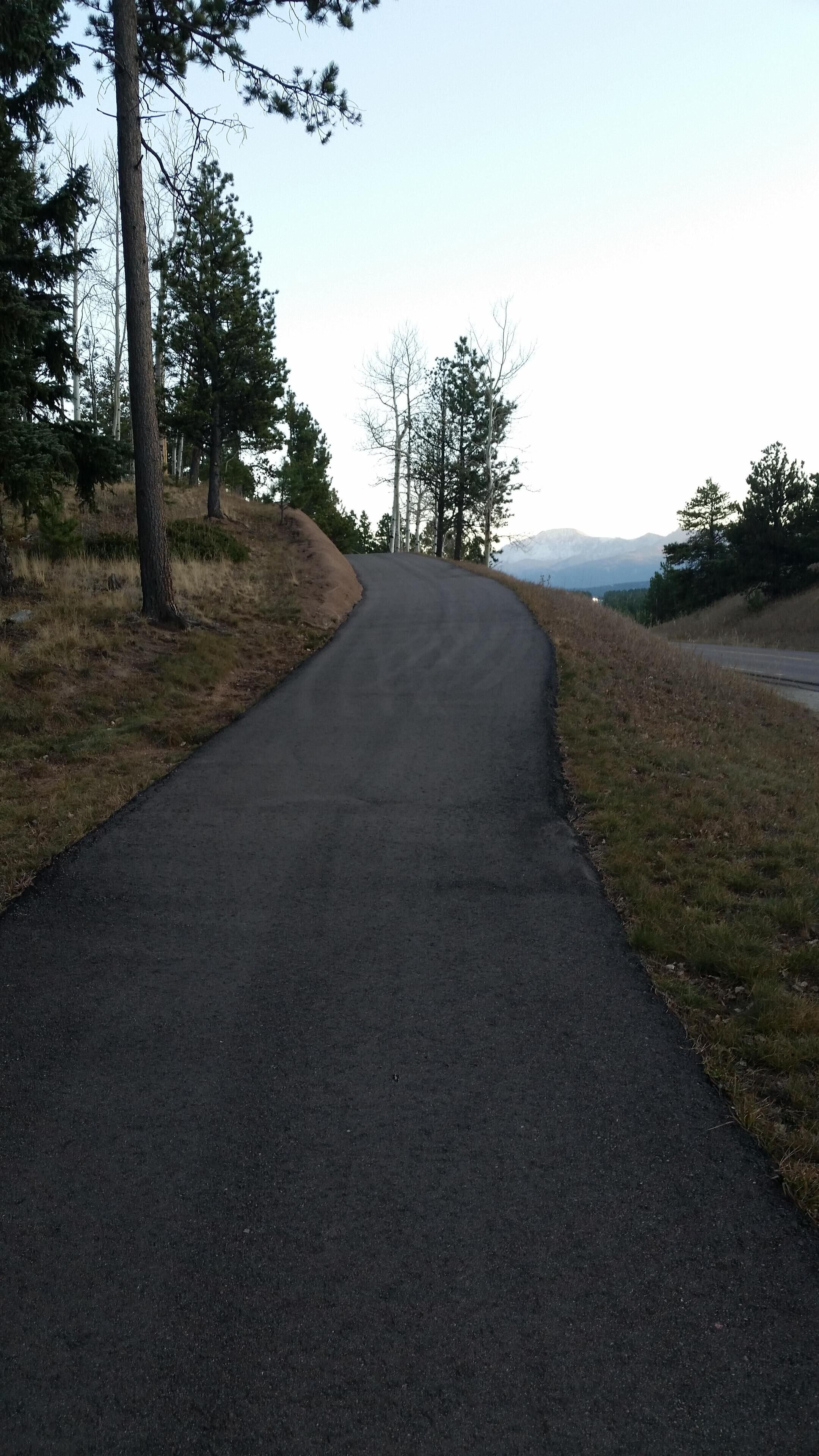 A paved road curving through a natural landscape with trees on both sides.