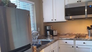 A kitchen with white cabinets, a stainless steel refrigerator, a microwave, and a coffee maker. - Cozy guest apartment conveniently located to all Woodland Park attractions (Woodland Park)