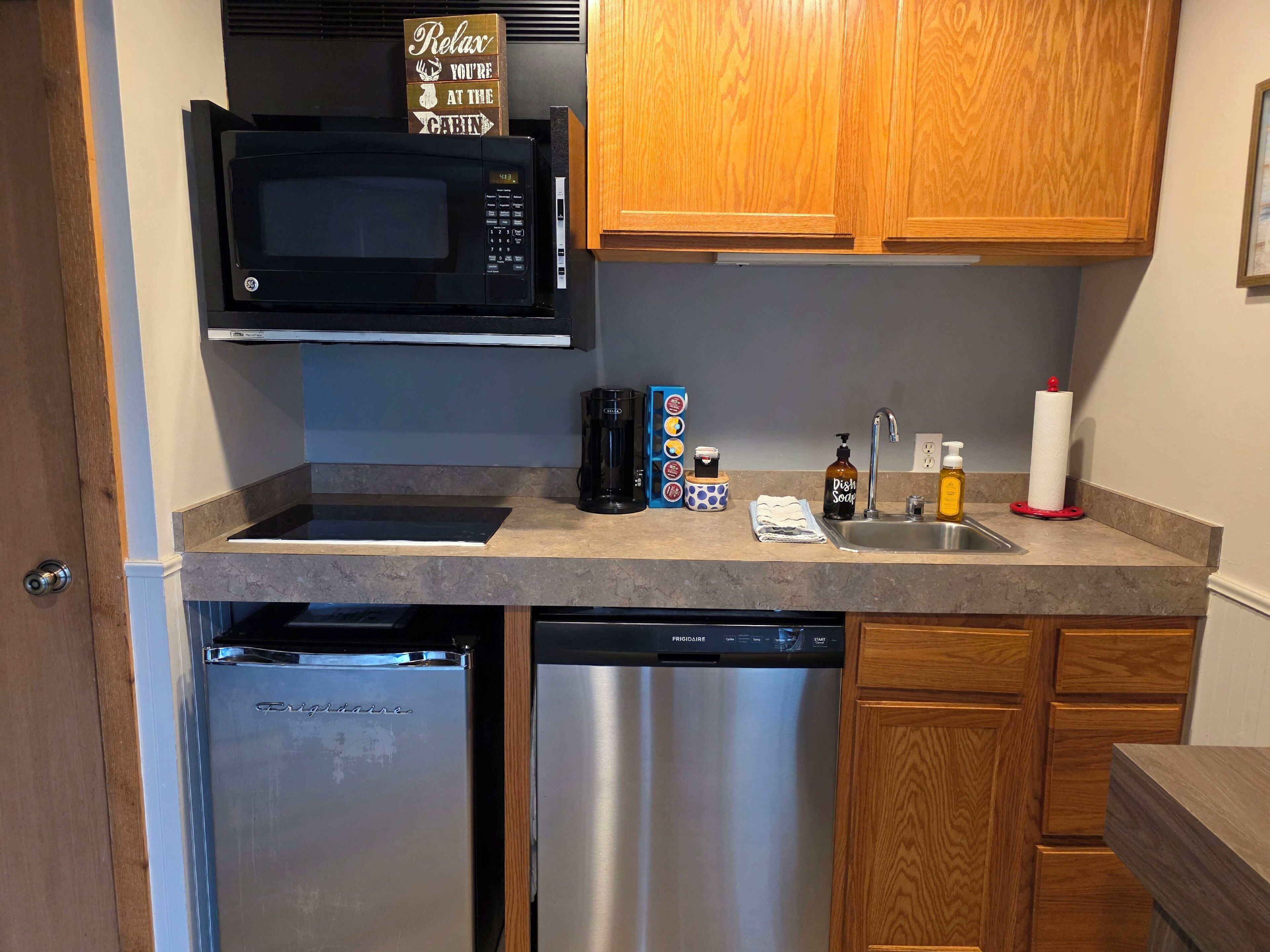 A compact kitchen with a built-in microwave, coffee maker, and dishwasher.