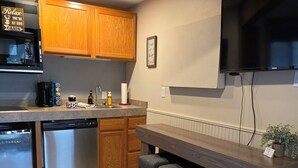 Una cocina con armarios de madera, microondas integrado, cafetera y lavavajillas.