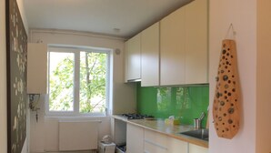 Une cuisine moderne avec des meubles blancs, un pare-feu vert et une fenêtre donnant sur les arbres.