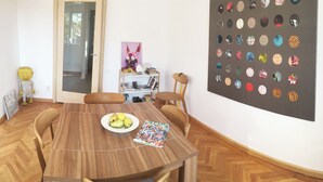 Un coin repas avec une table en bois, des chaises, une assiette de fruits et une œuvre d’art murale.