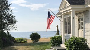 Une maison avec un porche à l’avant, un drapeau et une vue sur la mer.